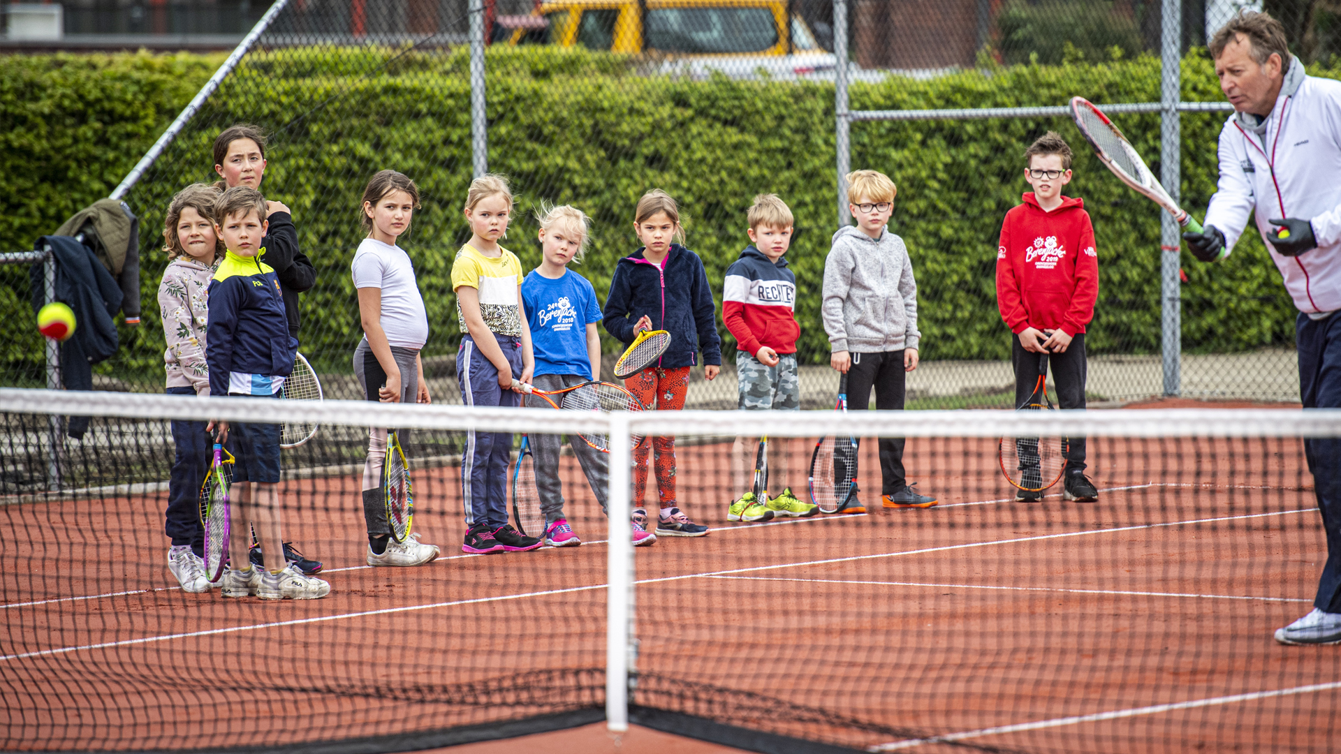 trainer met pupillen op de tennisbaan